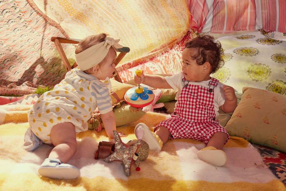 Two babies in a tent filled with toys 