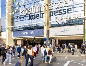 A crowd of people walking towards the entrance of the Kind + Jugend trade show