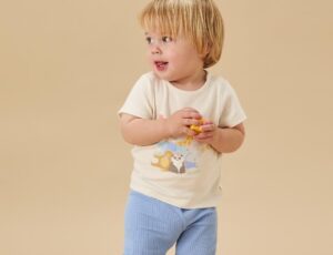 A child in an Animals Party T-shirt and blue leggings by MORI