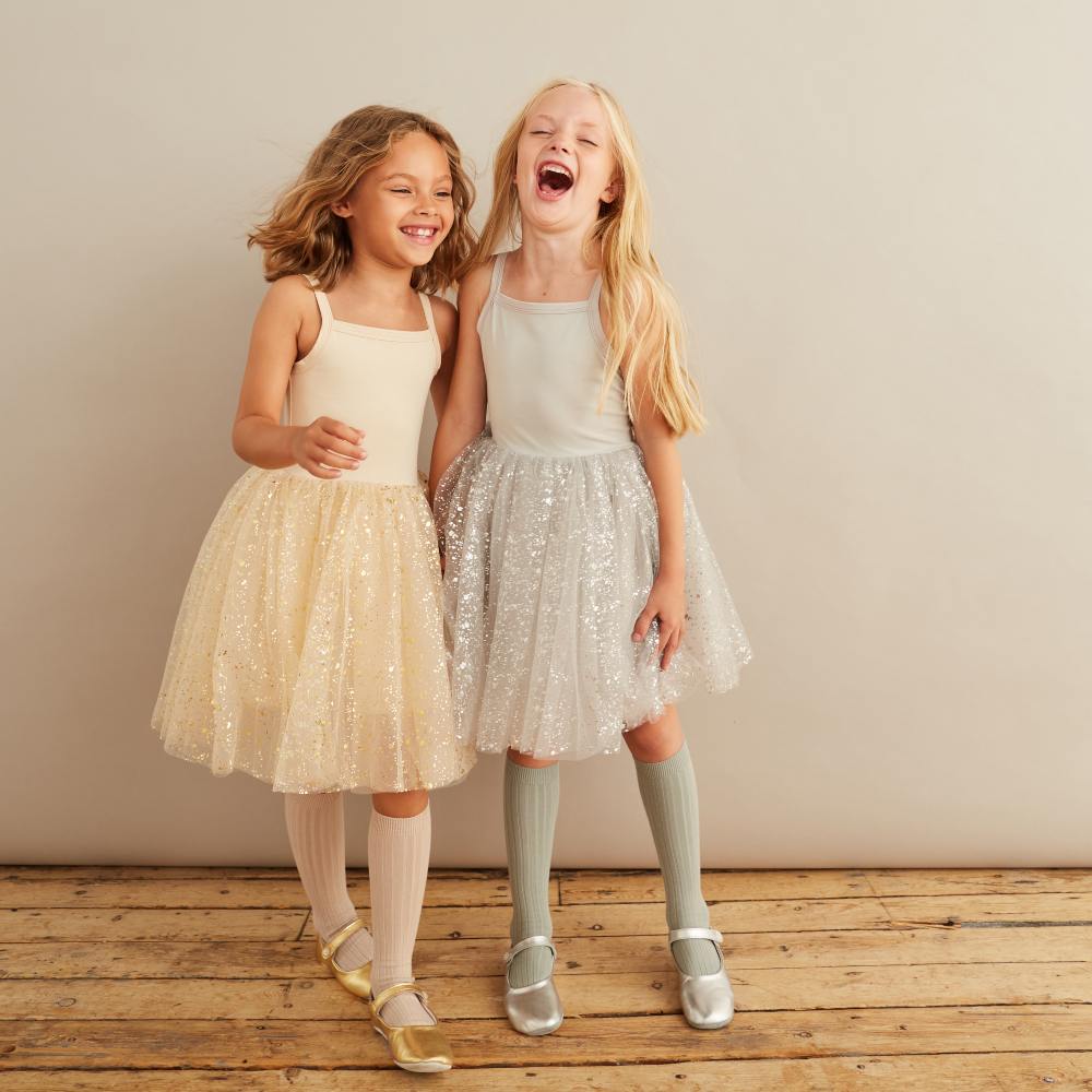 Two girls stood hugging wearing party dresses by Bob & Blossom 