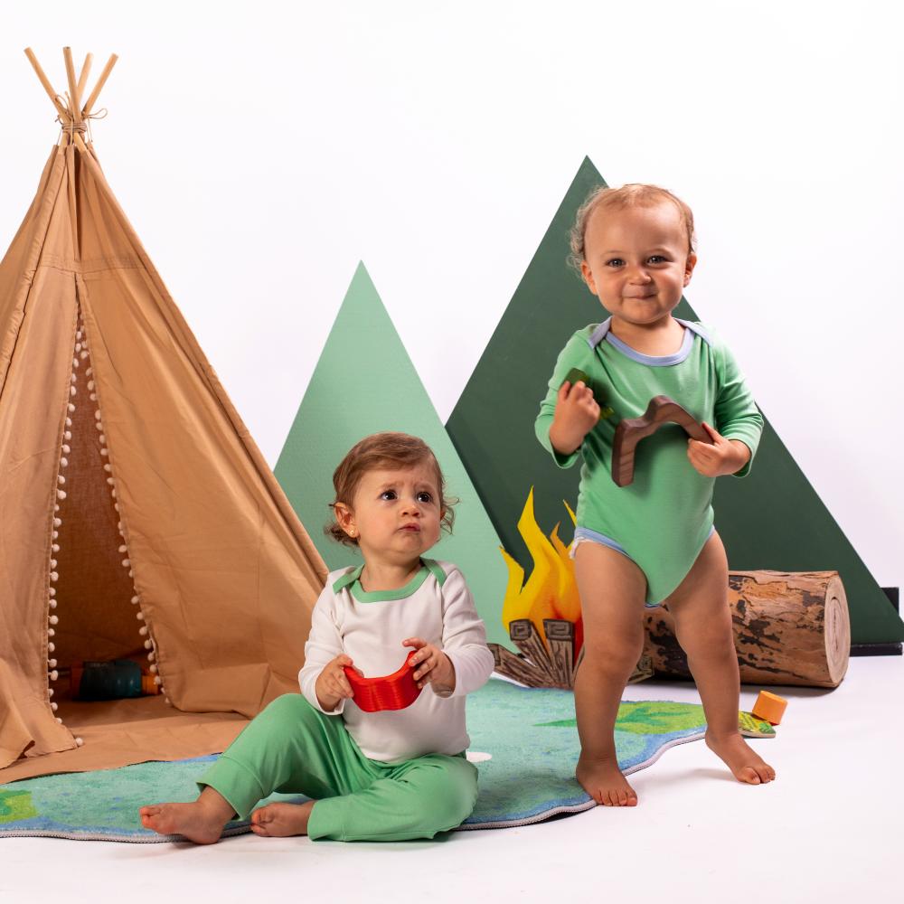 Two young children in front of a tents and a mock campfire scene 