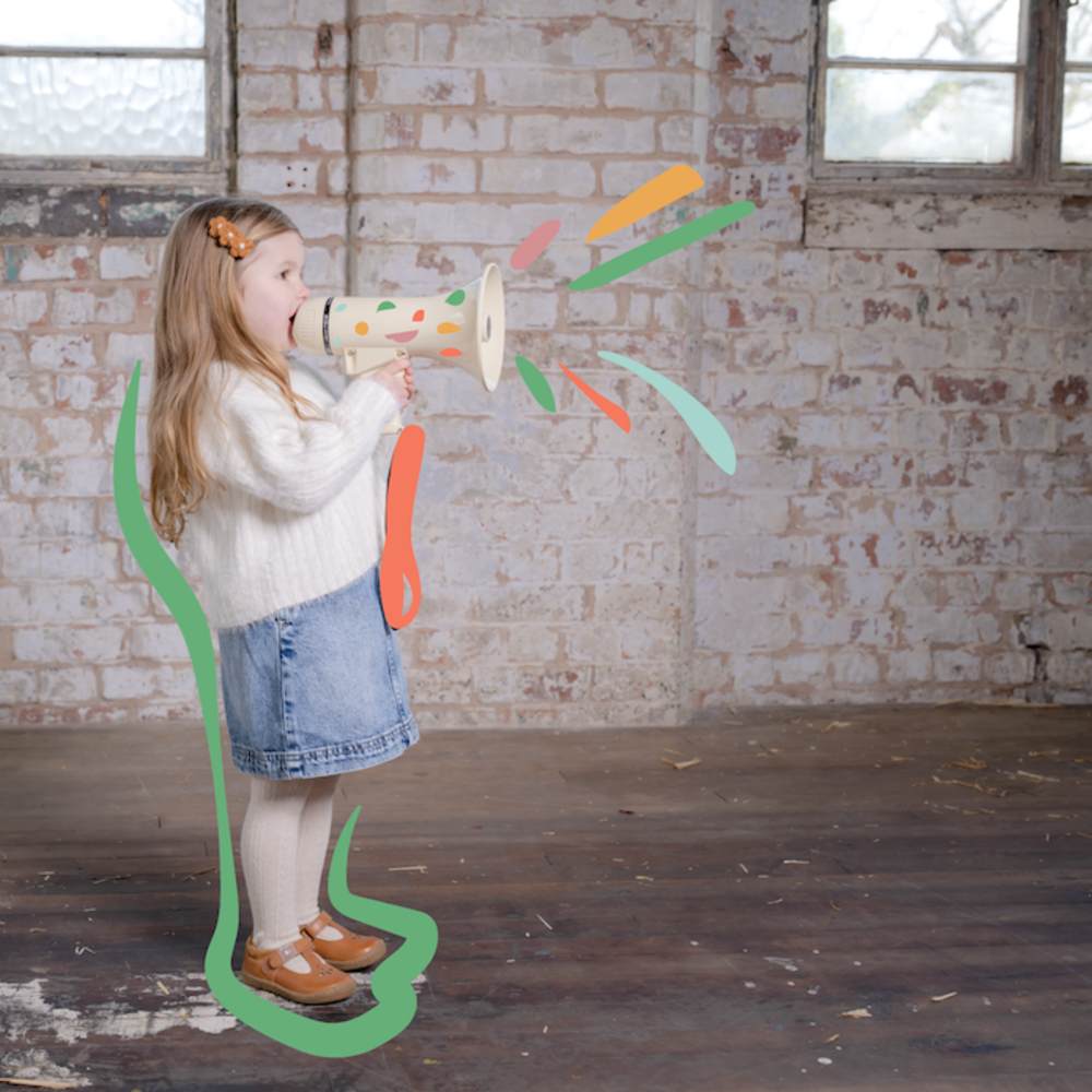 A young girl in a room holding up a megaphone to her mouth 