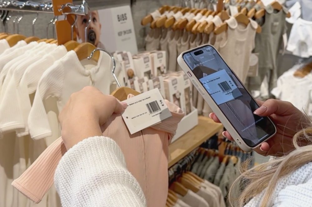 Someone scanning children's clothing with their phone in-store using the Mamas & Papas App