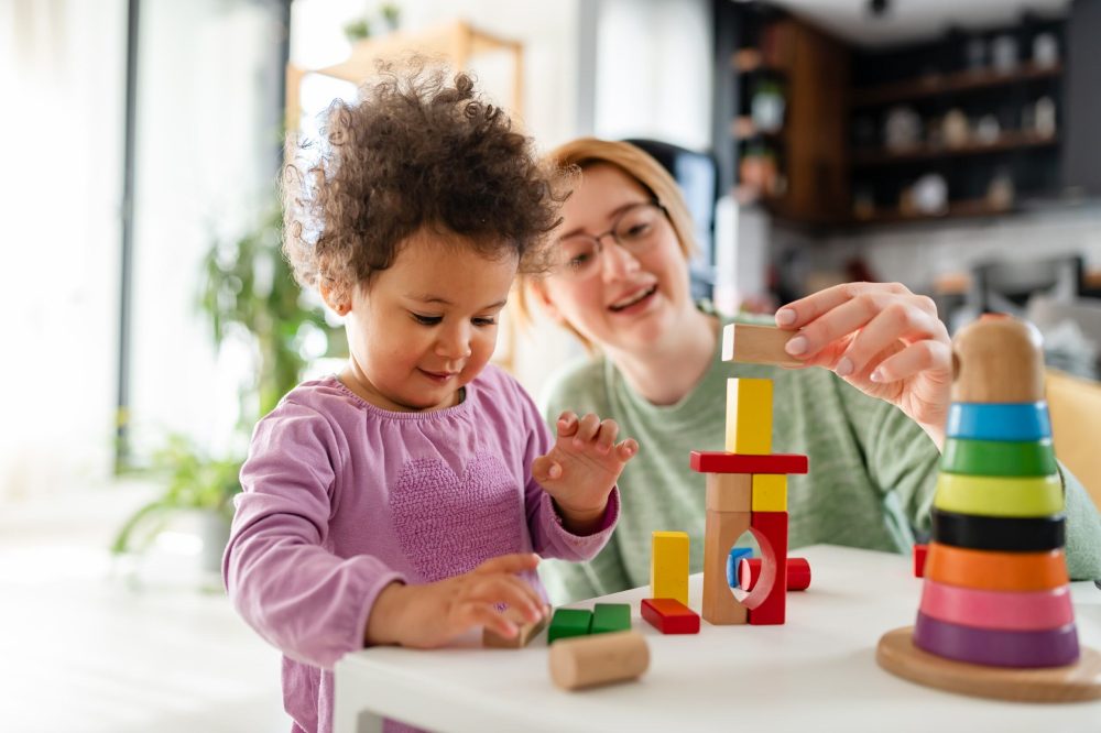 A child and a woman playing with wooden toys at a table