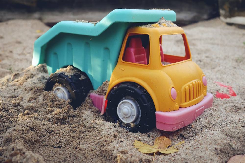A plastic toy dumper truck in a sandpit