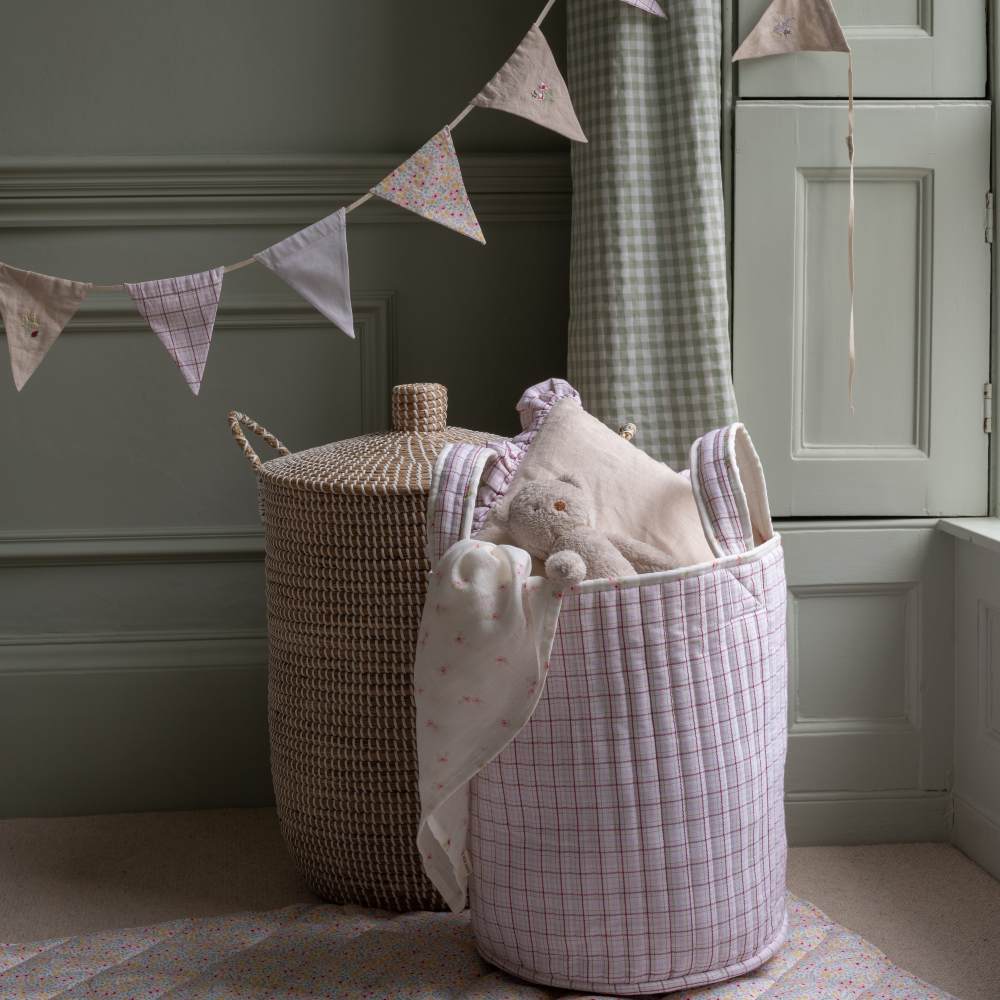 Fabric storage and laundry baskets in a green panelled room decorated in bunting 