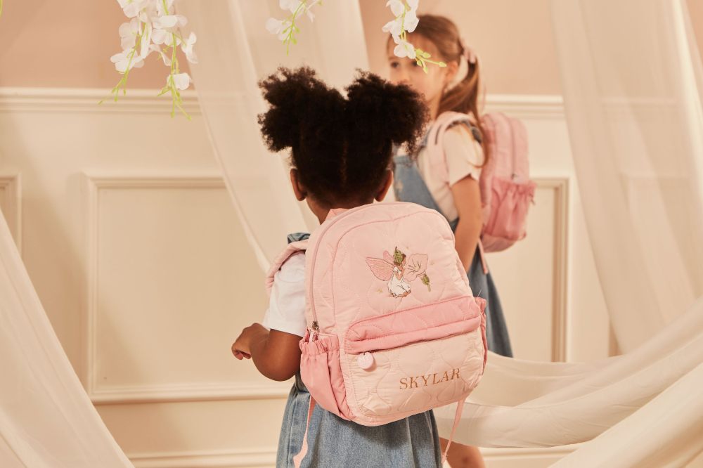 Two children wearing pink backpacks with Flower Fairies on them 