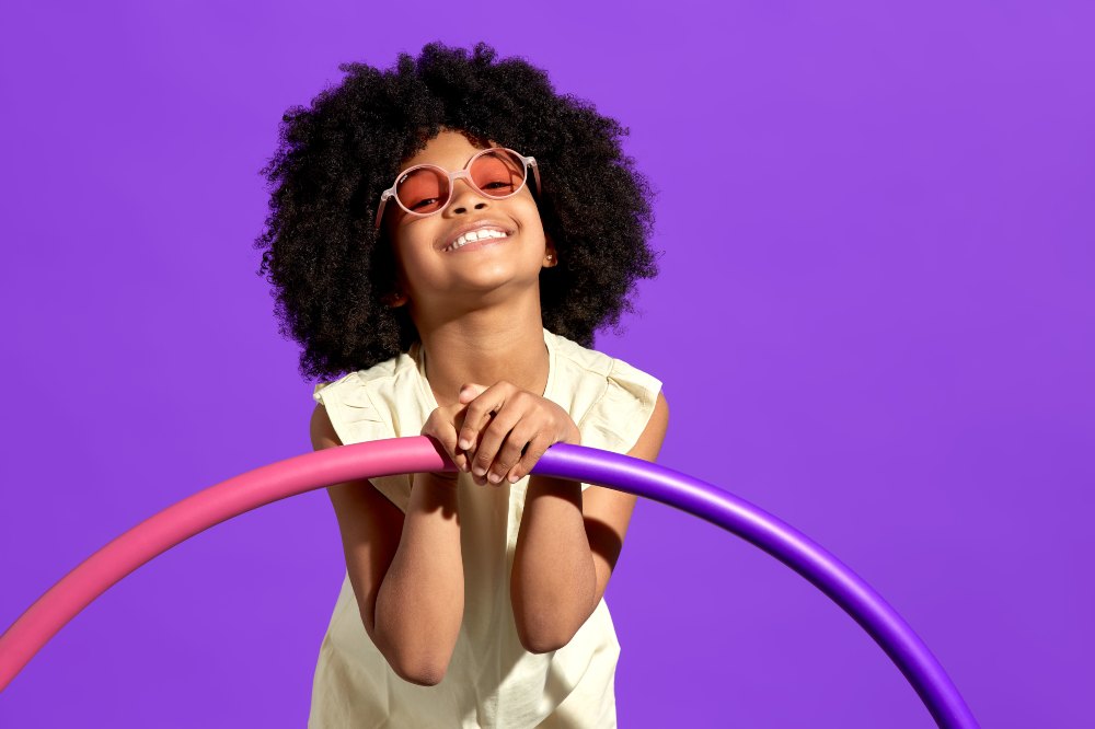 A girl wearing sunglasses holding a hula hoop