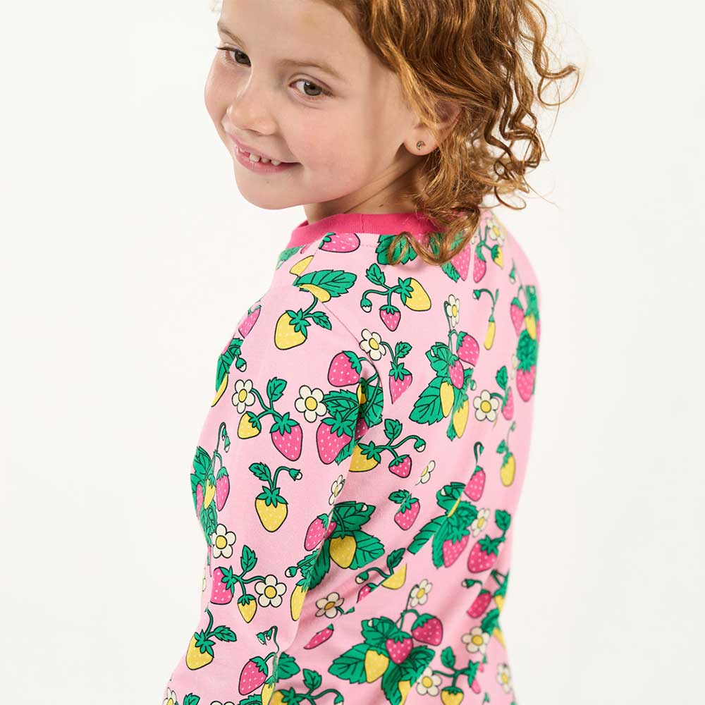 A young girl wearing a pink top with strawberry pattern