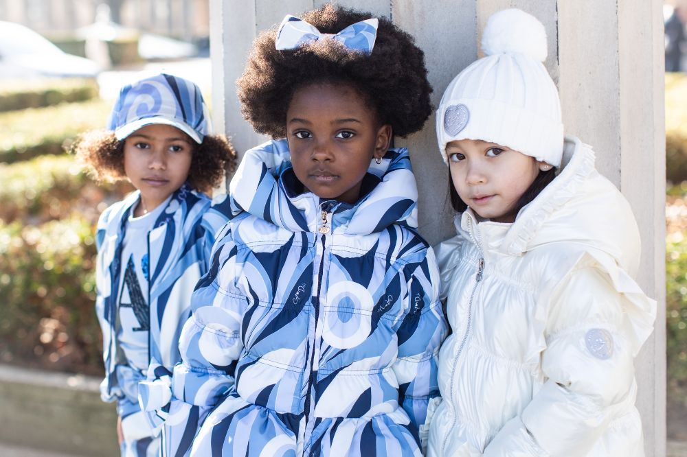 Three girls stood outside in blue outfits by A Dee by Picture Book Fashion