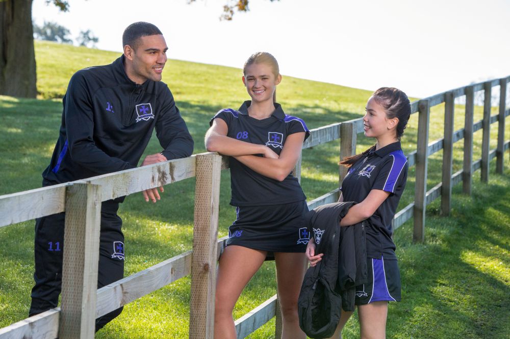 Three people stood by a fence in a field wearing teamwear by Chadwick