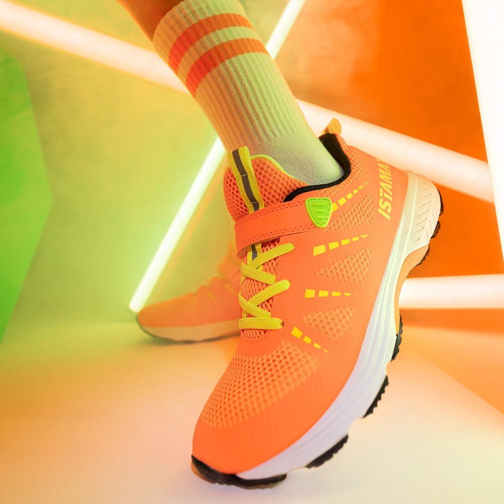 A close up of a child's foot wearing an orange Istamax trainer 