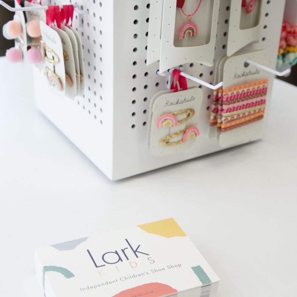 Lark Kids business cards displayed next to a stand of Rockahula Kids hair accessories