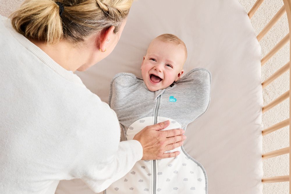A woman leaning down to a baby in a crib