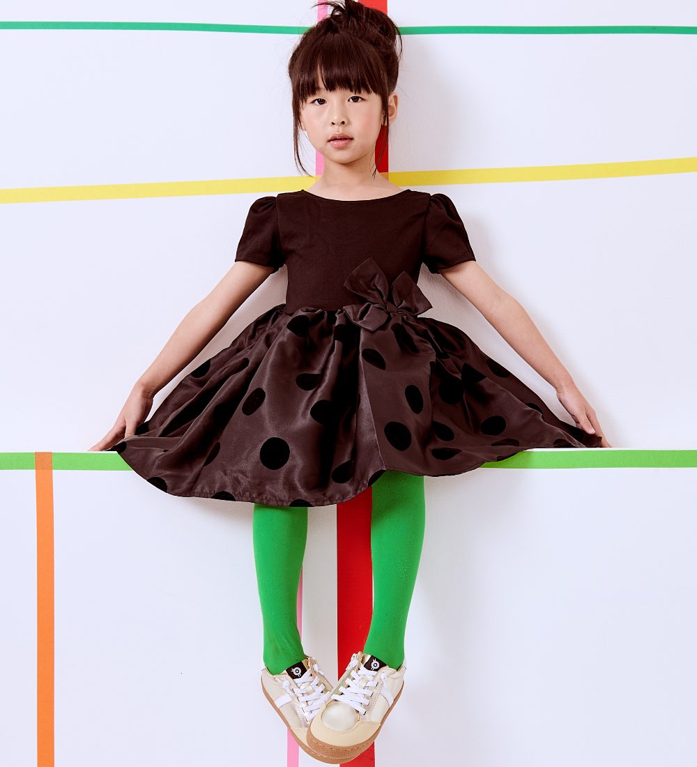 A young girl in a black tutu skirt dress and Old Soles trainers 