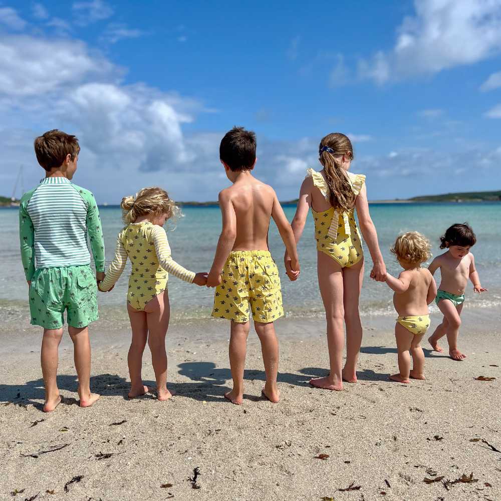 A row of children stood on a beach in swimwear 