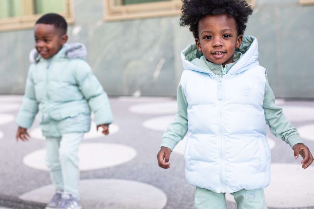 Two boys stood outside wearing pale blue and green outfits by Mitch & Son