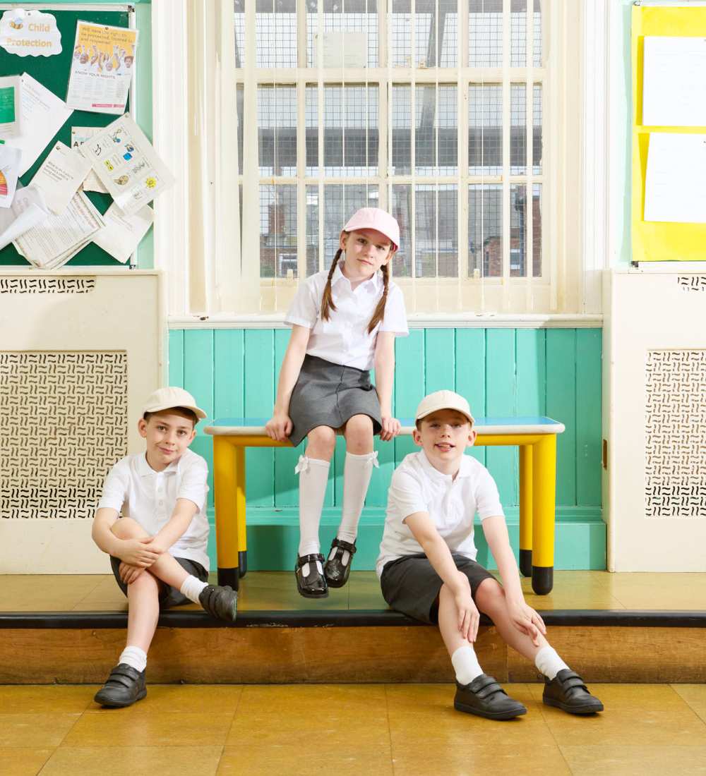 Three school children sat in a classroom wearing uniform and ToeZone school shoes 