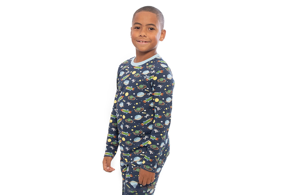 A young boy stood wearing dark blue pyjamas with a space theme pattern