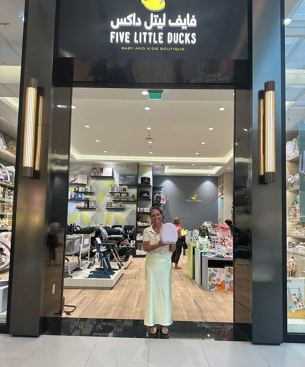 Amanda Jenner stood holding a My Carry Potty in the door way of a store