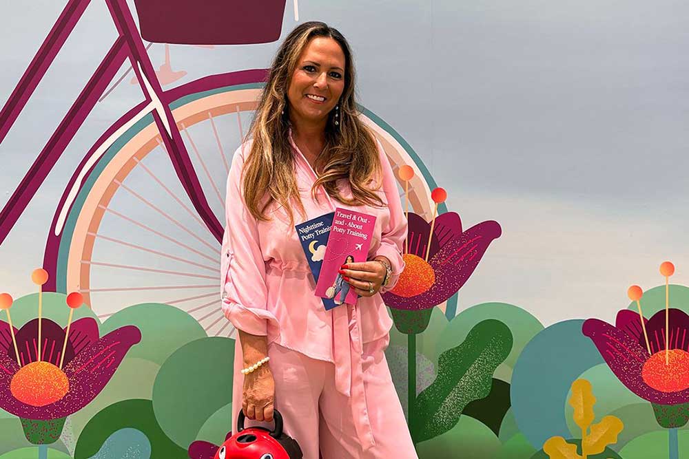 Founder Amanda Jenner stood holding a My Carry Potty and training guides