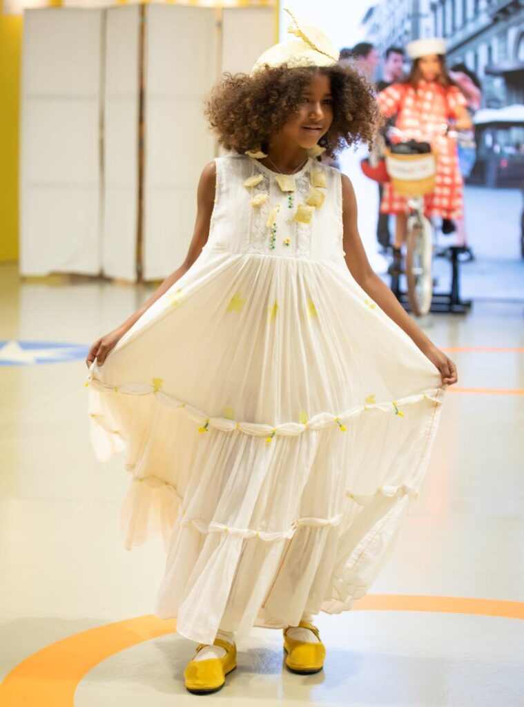 A child in a long yellow dress, hat and shoes in the Pirouette Parade 
