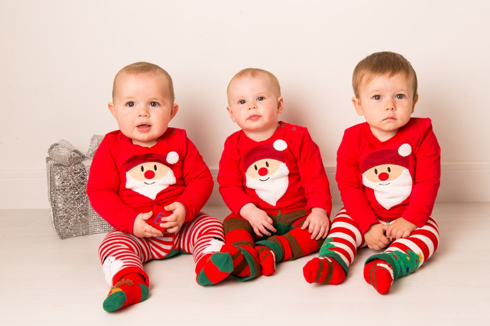 Three babies sat on the floor wearing matching Christmas outfits by Blade & Rose
