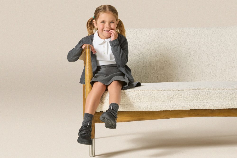 A young girl in school uniform sat on a white sofa