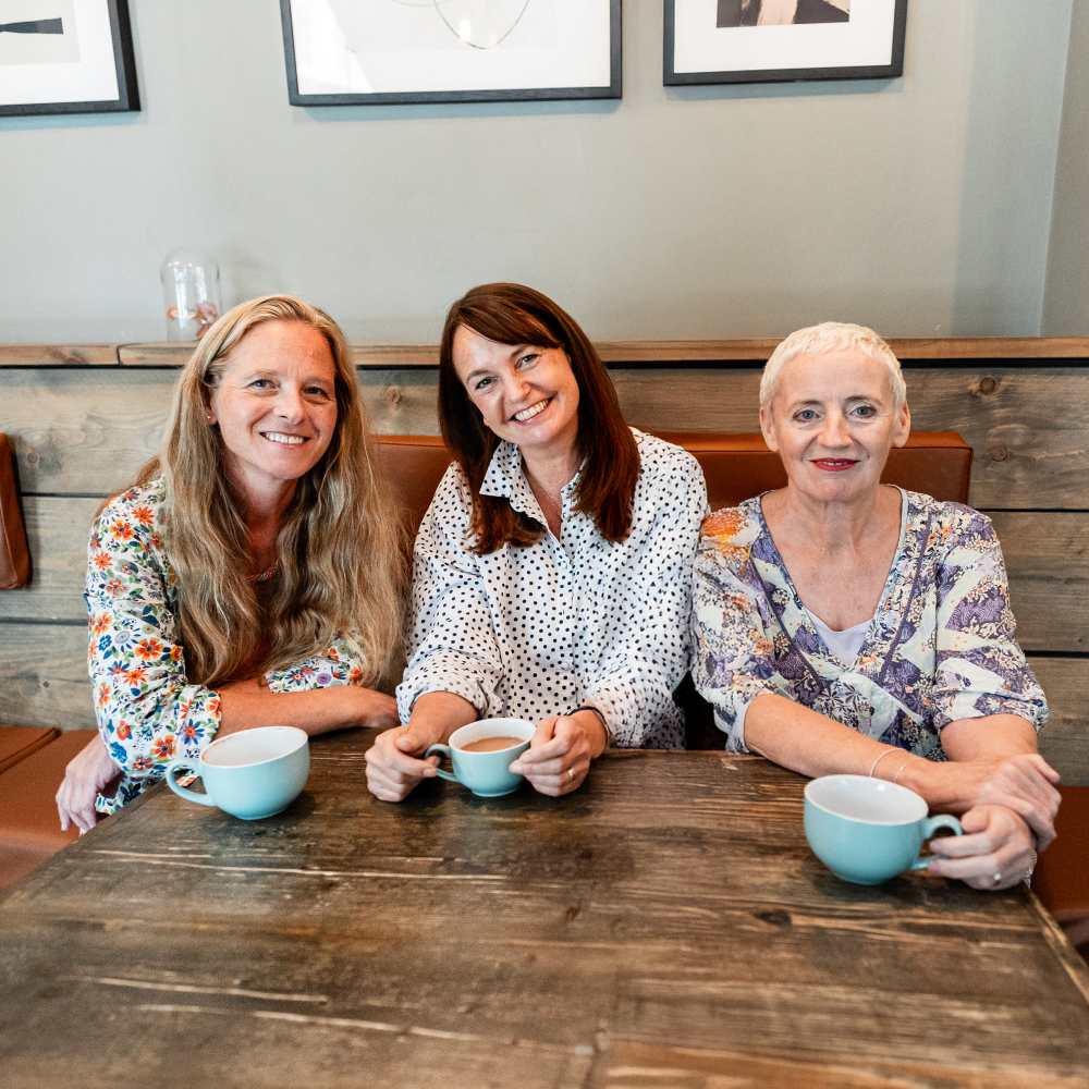 Three woman, the founders of Folk & Thread, sat at a table with drinks 