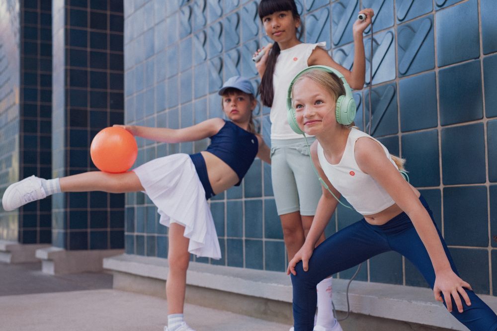 Three girls in front of a blue tiled wall in activewear 