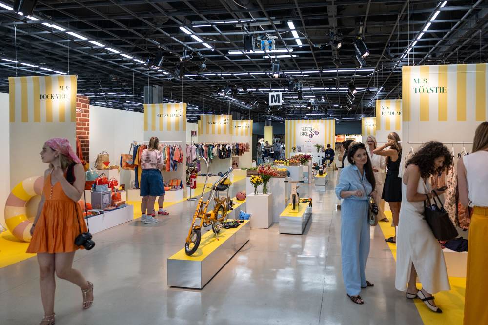 People stood in a hall looking at exhibition stands at Pitti Bimbo 101