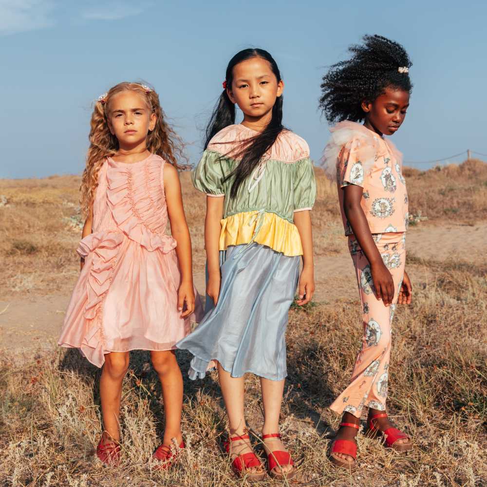Three girls stood outside wearing red shoes 
