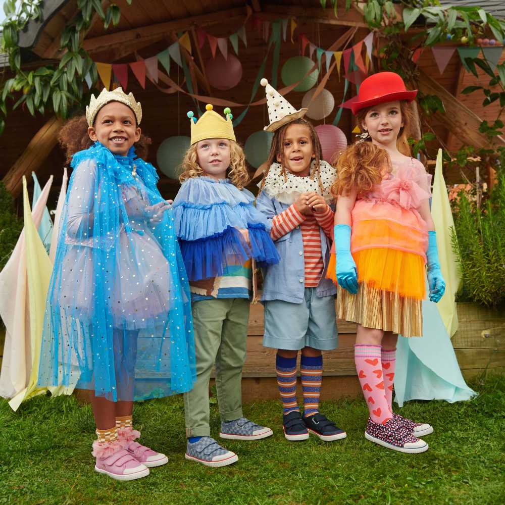 A group of children stood outside in brightly coloured costumes and shoes by Start-Rite