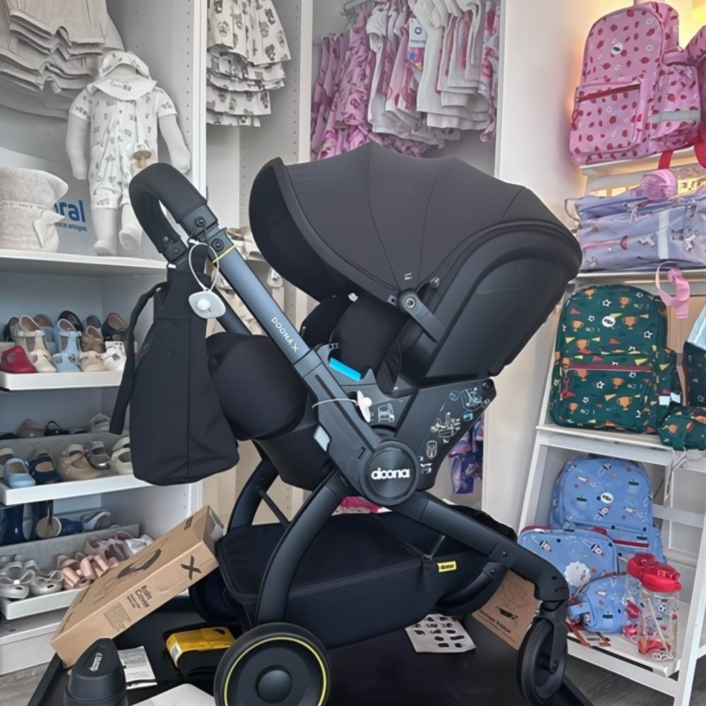 A pram displayed with baby and children's clothes in the This Little Piggy store 