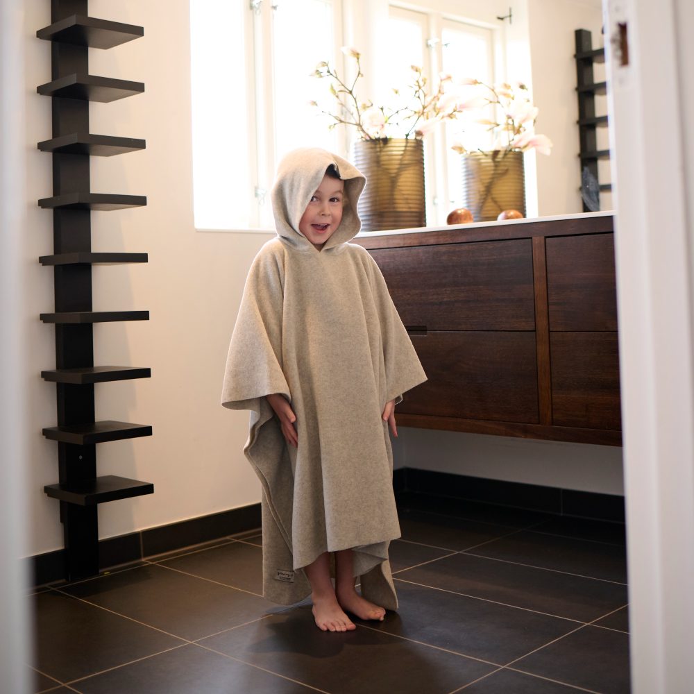 A child stood in a bathroom wearing a hooded robe