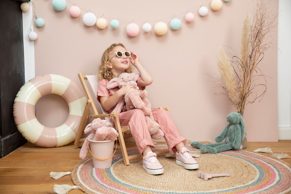 A girl sat in a deck chair in a room with rabbit plush toys by Happy Horse