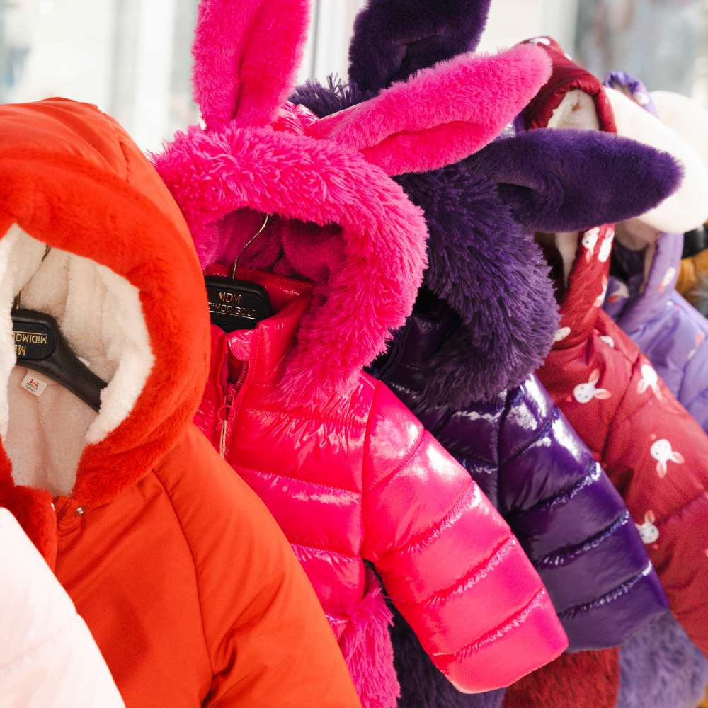 A rail of brightly coloured children's coats with rabbit ears 