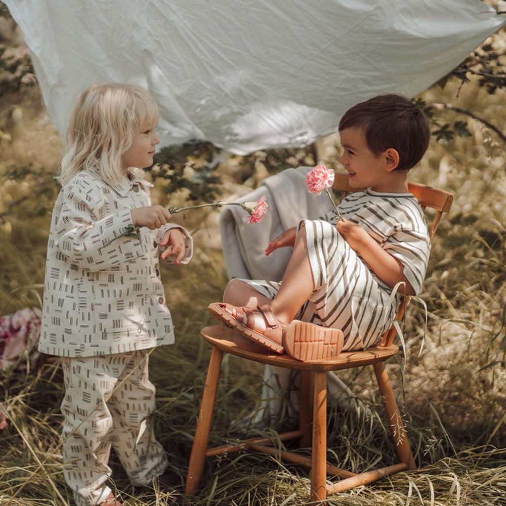 Two children playing outside in a field beneath a sun shade 