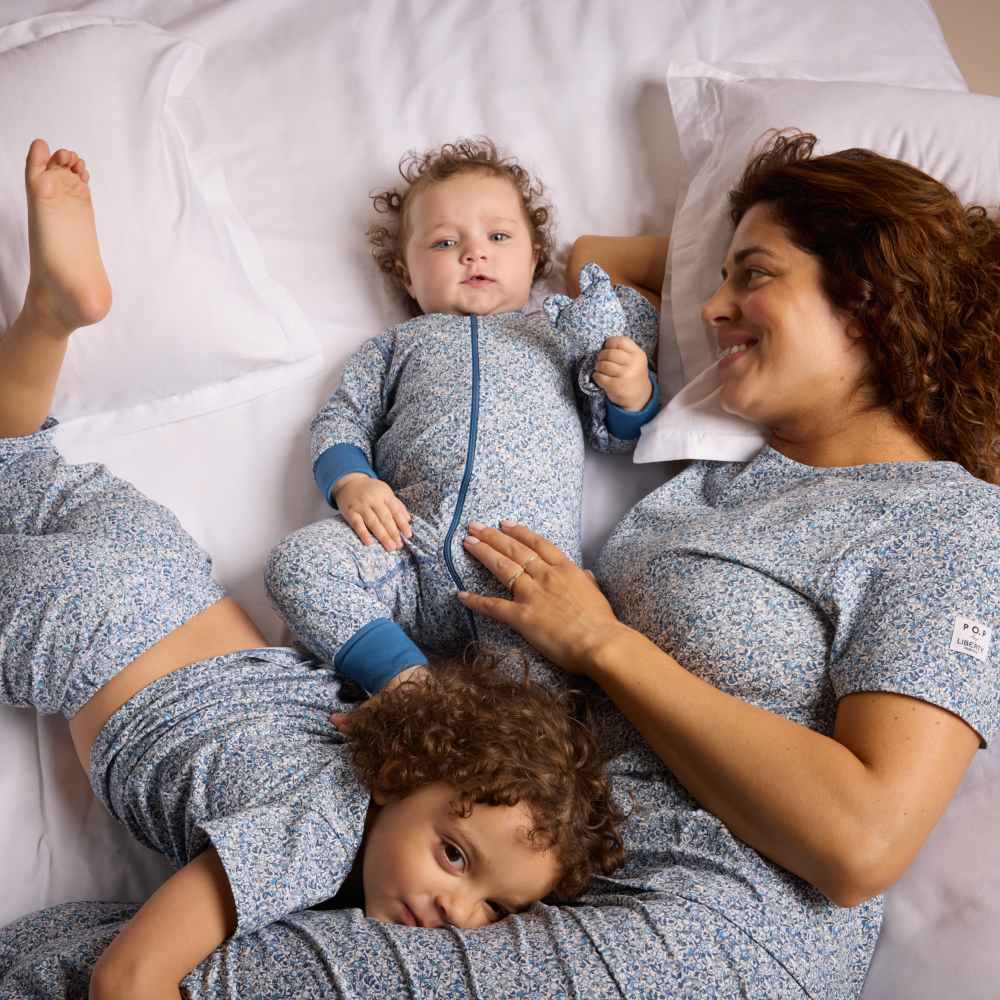 A woman lying on a bed with two children all wearing matching pyjamas from the PO.P Liberty Fabrics collection 