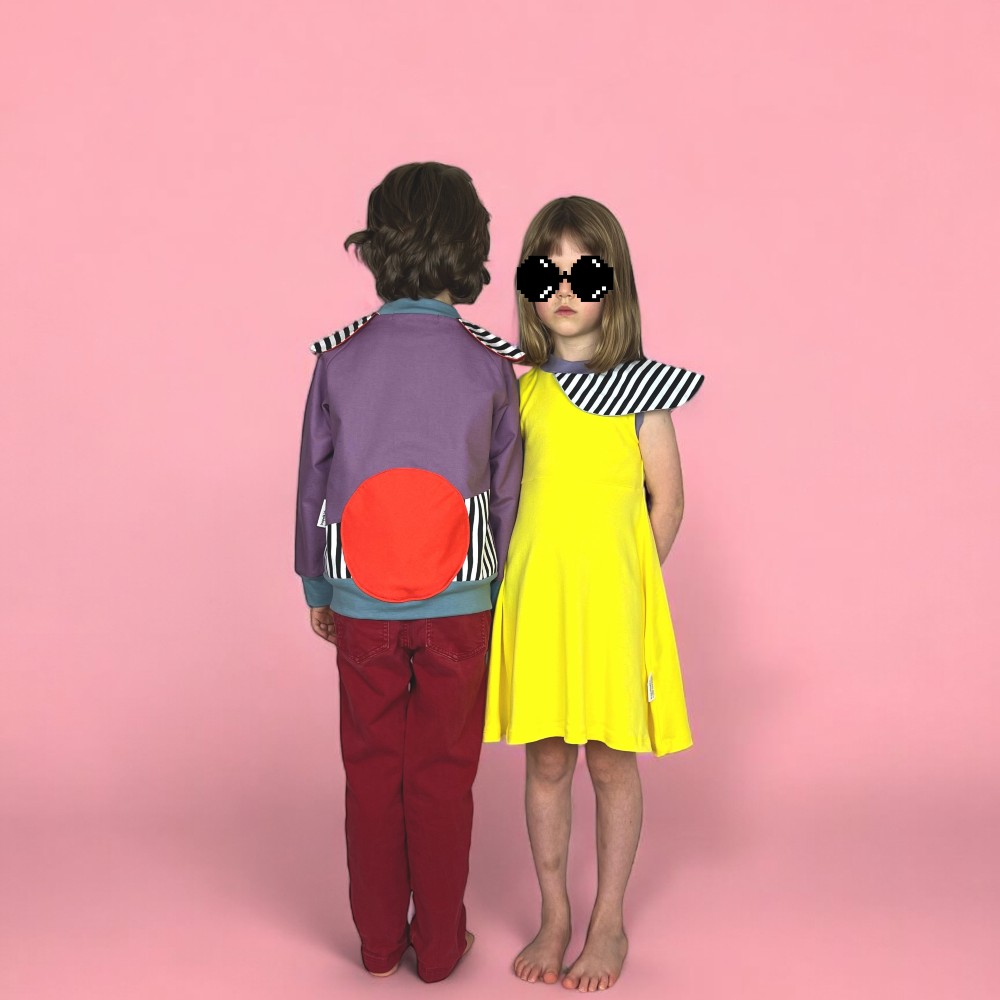 Two children stood against a pink background wearing bright outfits by Tropel Kids