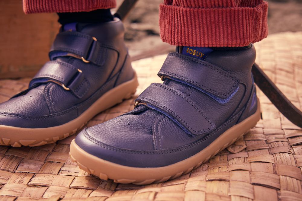 A child's feet shown wearing dark blue shoes by Bobux