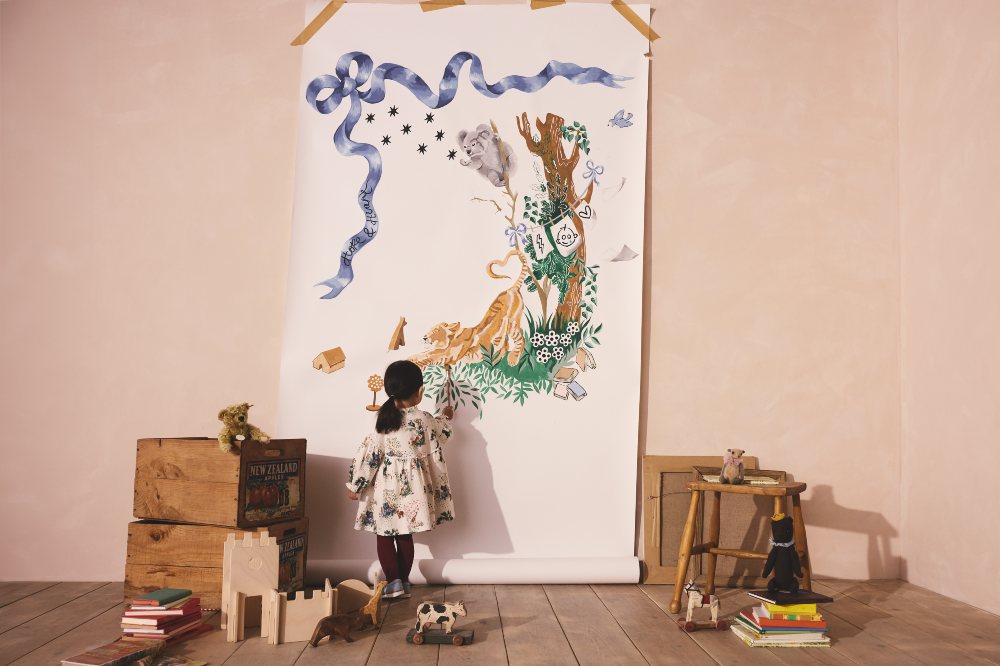A girl stood in a room at a painting wearing a dress from the Cathh Kidston x GOSH Charity collection