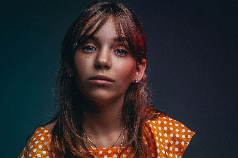 A professional image of a girl in a orange spotty dress against a dark background