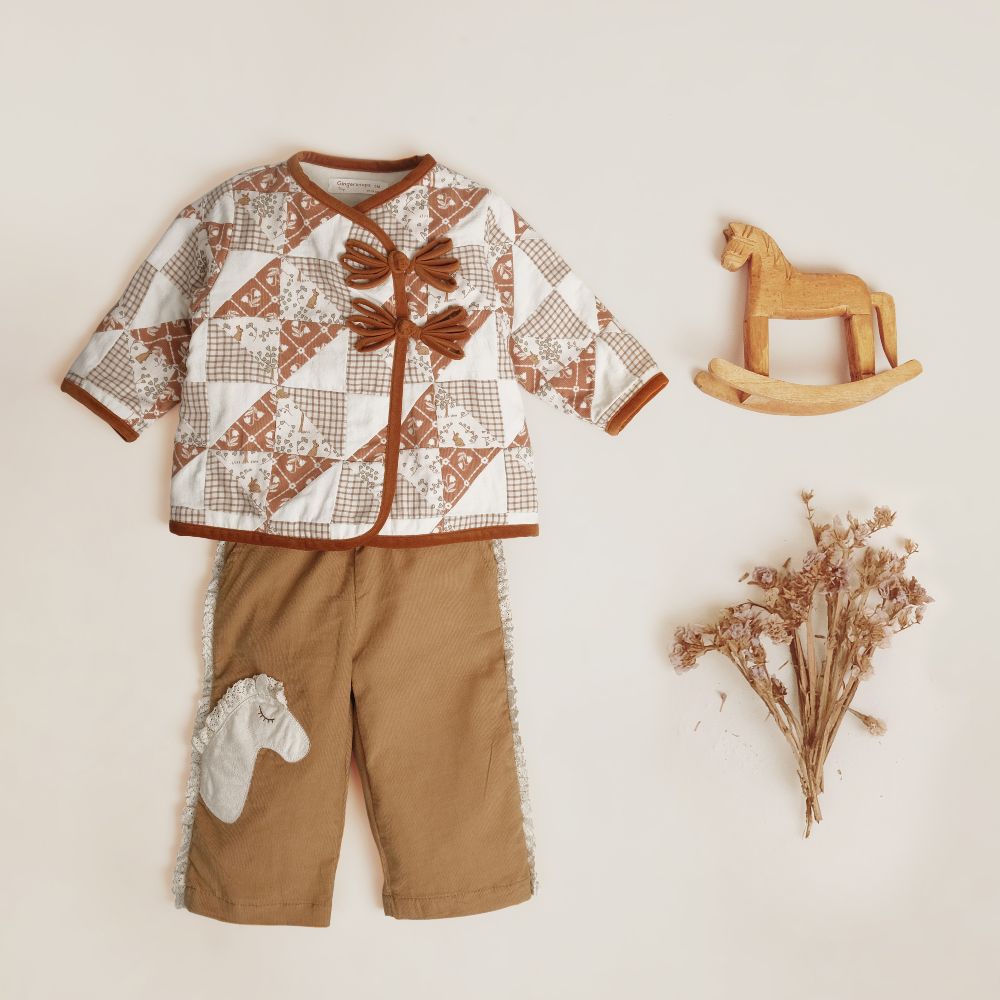 A children's outfit by Gingersnaps displayed on a white background beside a wooden toy and some dried flowers 