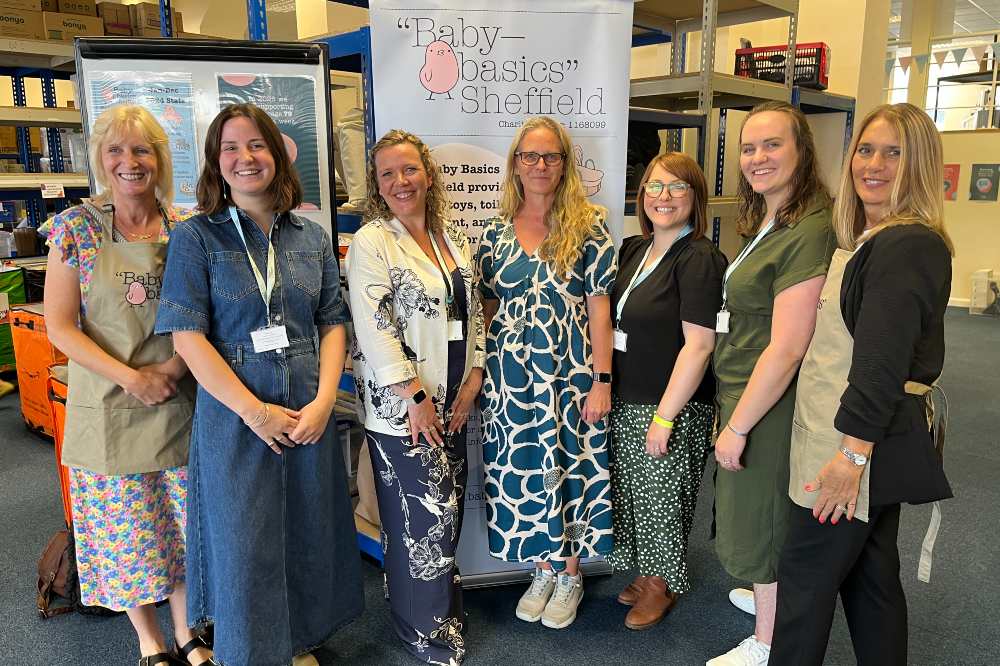 A group of people stood in a room in front of a sign saying Baby Basics
