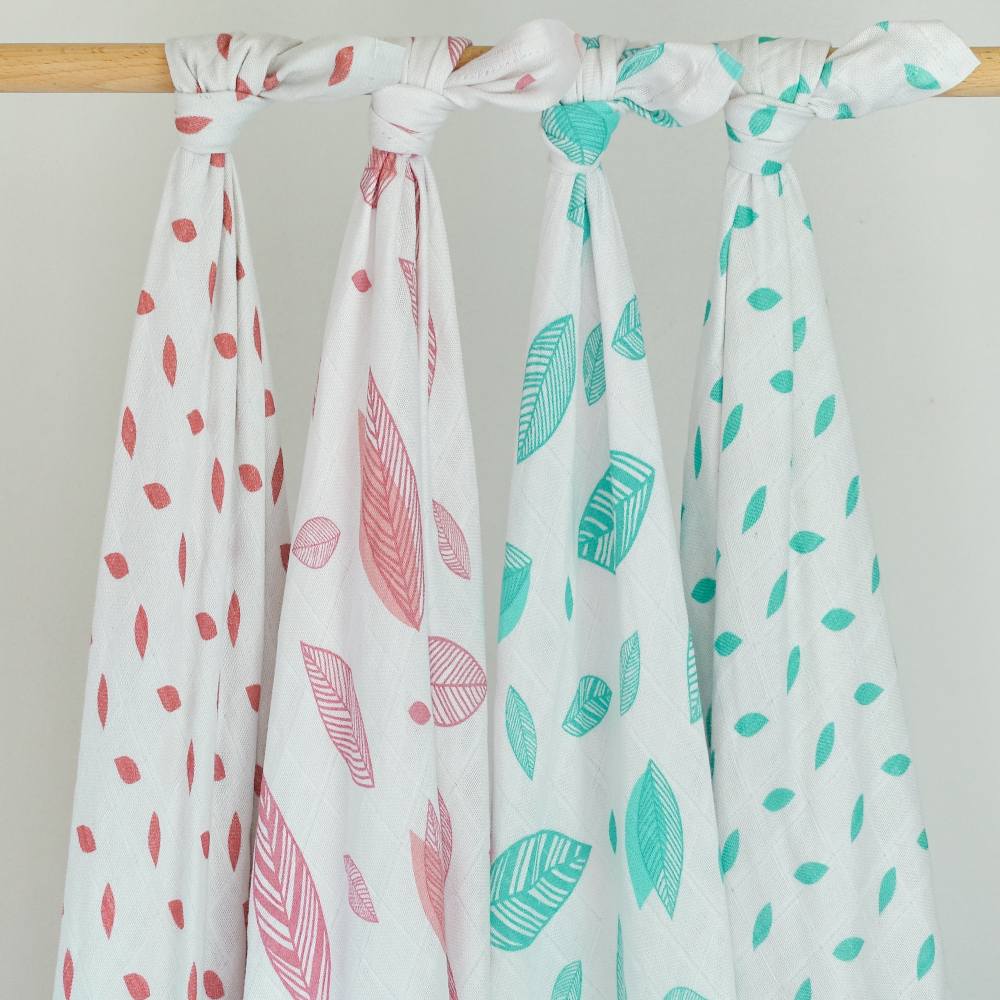 Four printed baby muslins hung on a wooden rail 