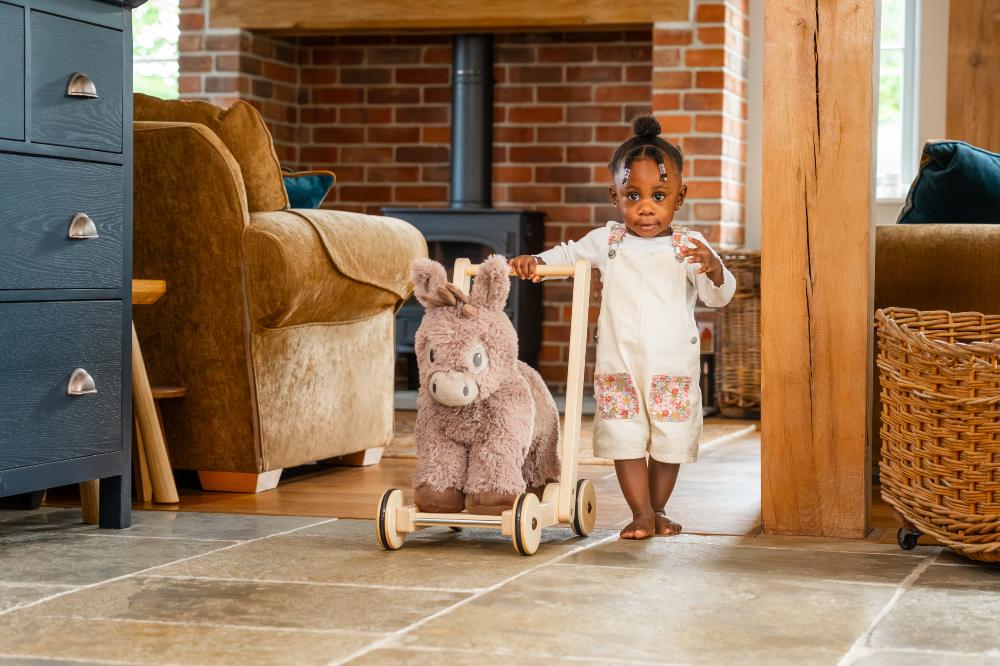 A young girl walking with a donkey baby walker by The Little Bird Told Me 