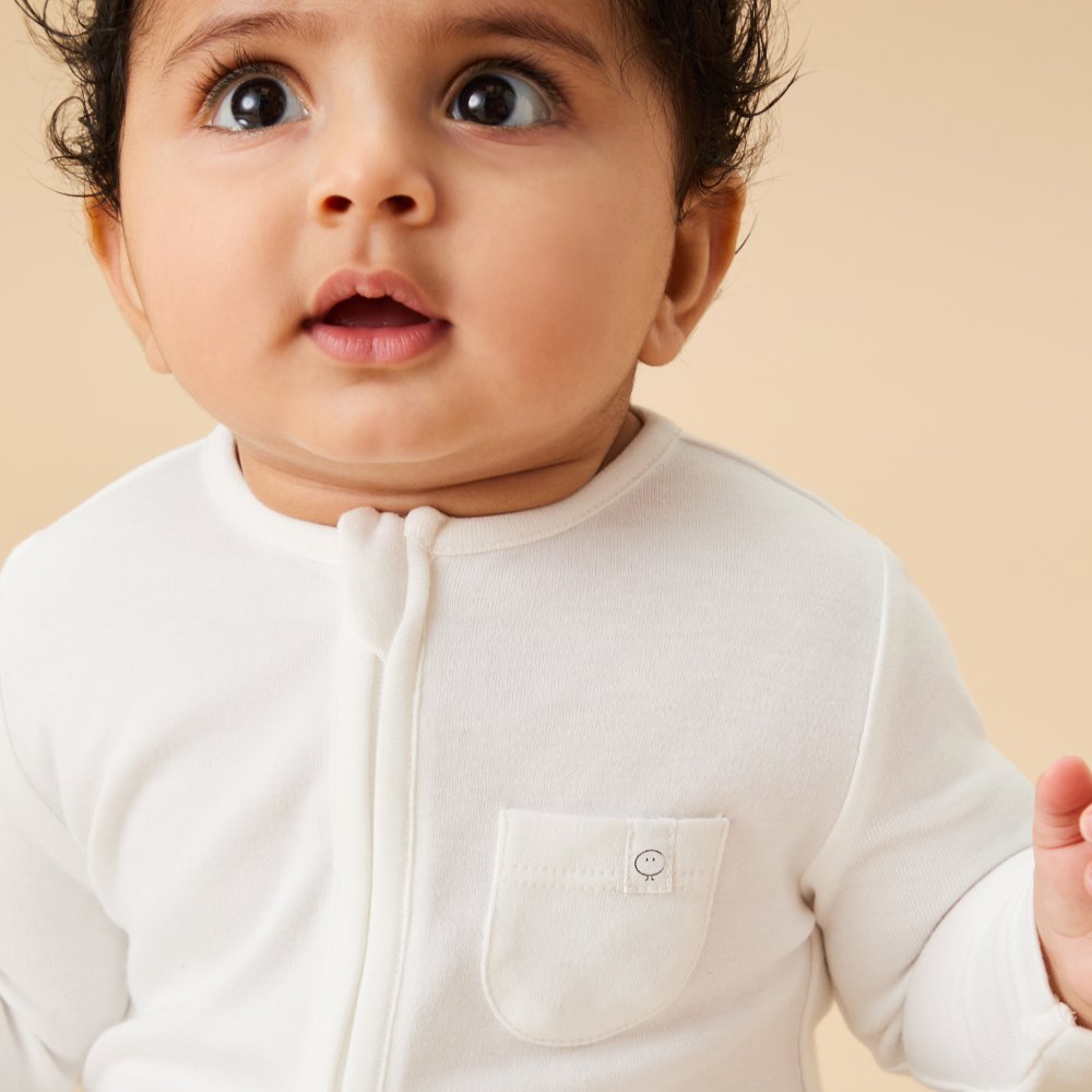 A baby wearing a white MORI babygro