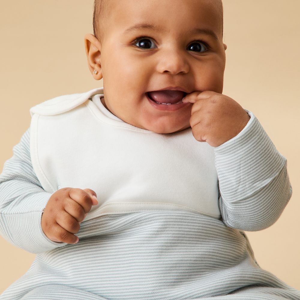 A smiling baby sat in a sleeping bag 