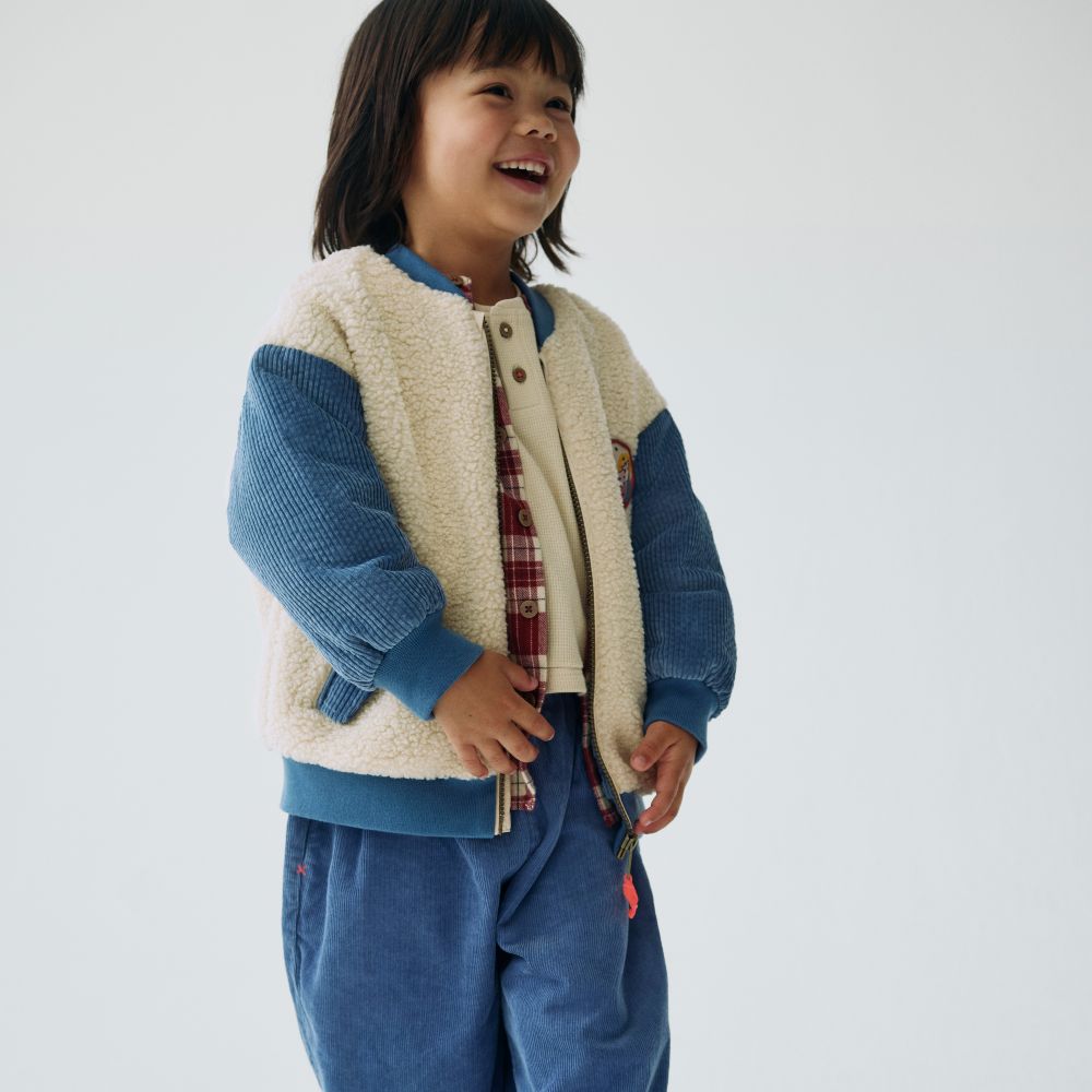 A girl in a blue corduroy and sheepskin outfit from the new M&S x Binky Kidswear collection 